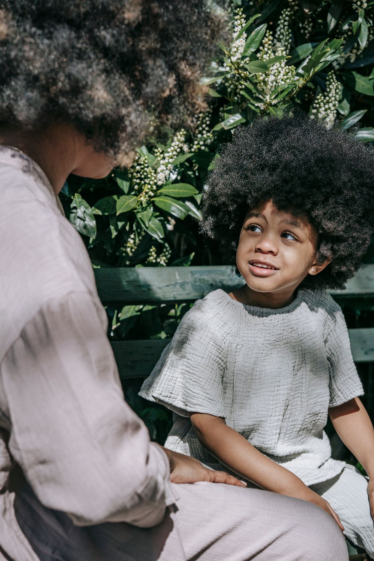 A woman and child talking on a park bench.