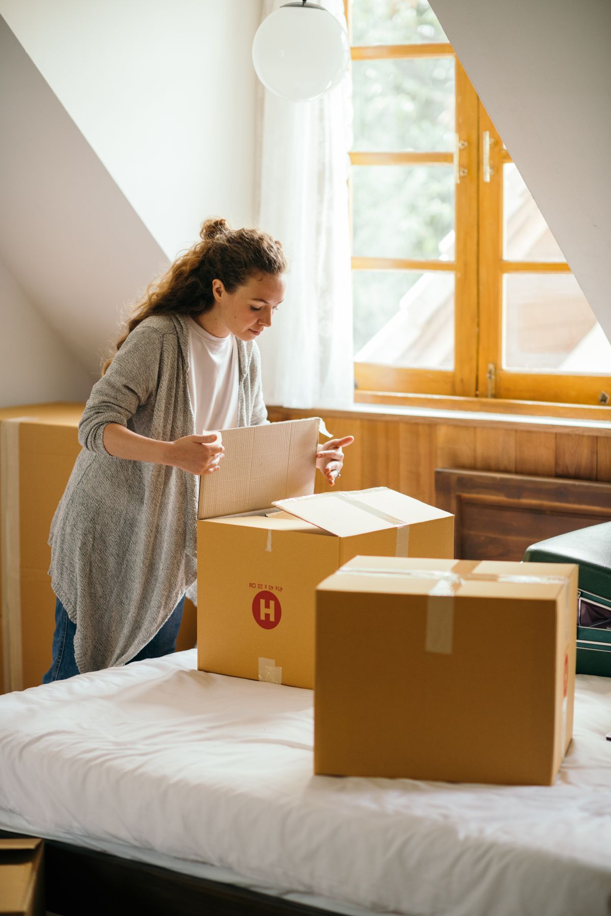 A woman arranging belongings beside moving boxes.