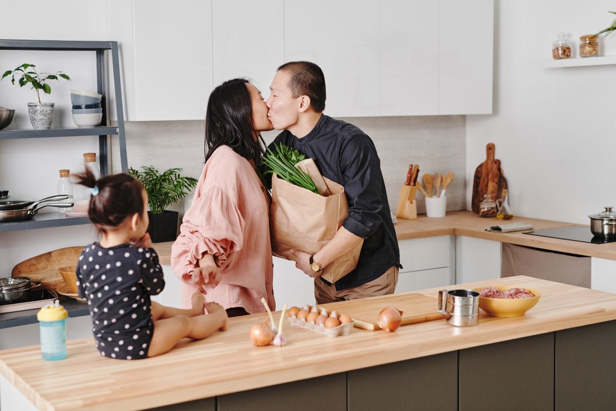 A family sharing a kitchen while preparing food.