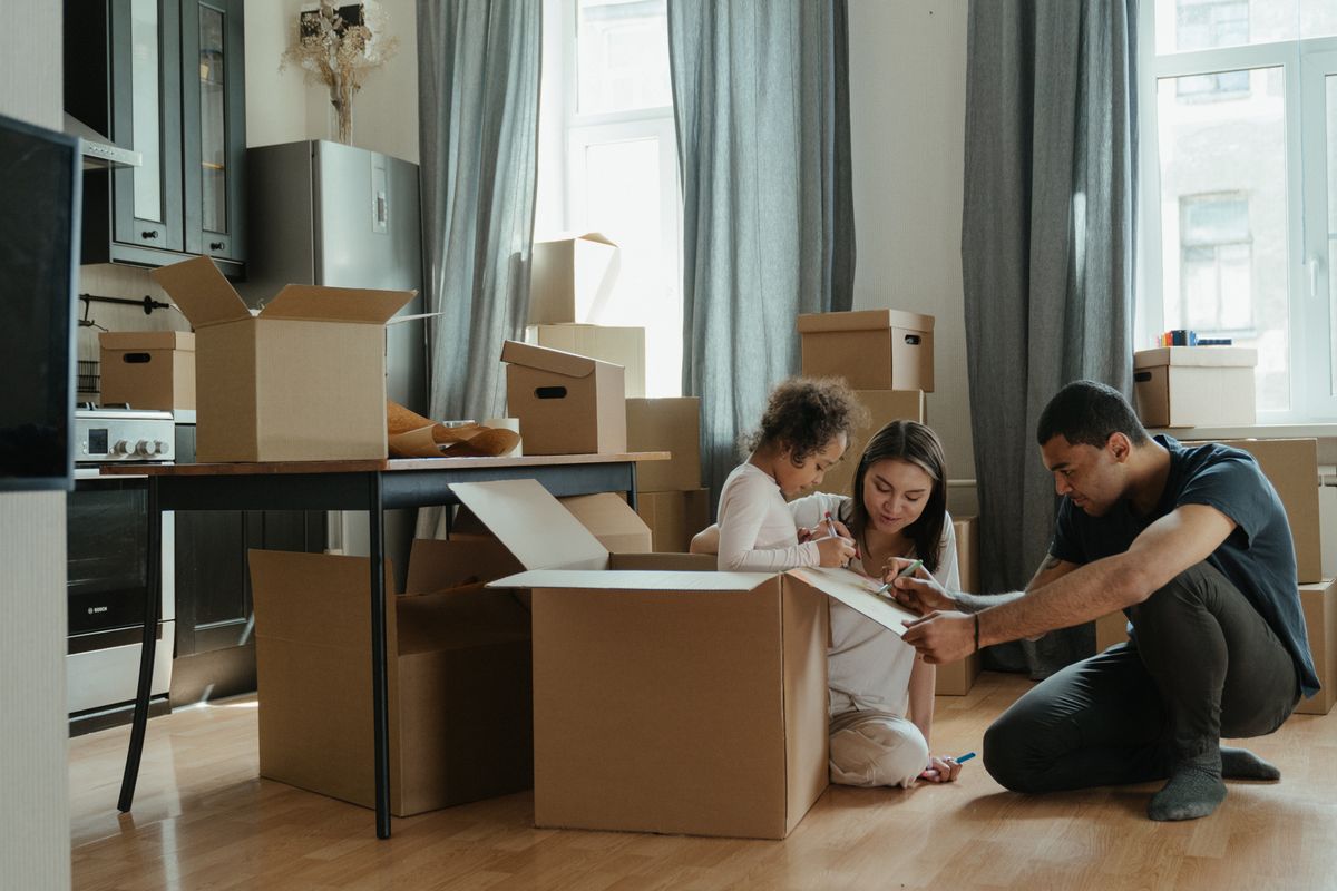 A family opening moving boxes on the floor of a new home.