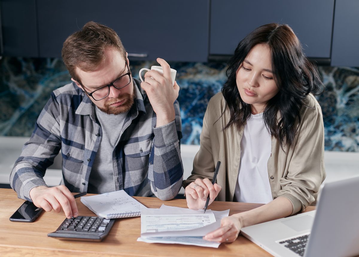 Two adults reviewing household bills with a calculator.