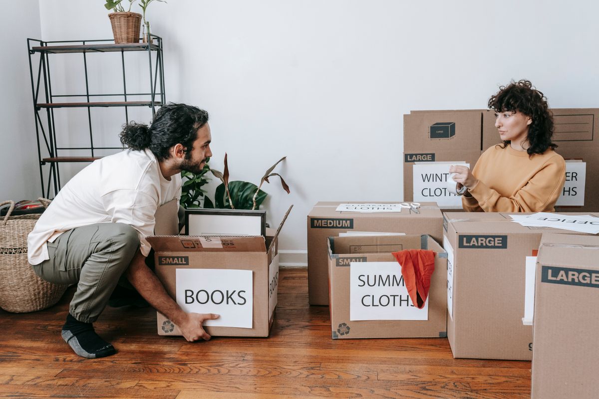Two people sorting and labelling moving boxes.