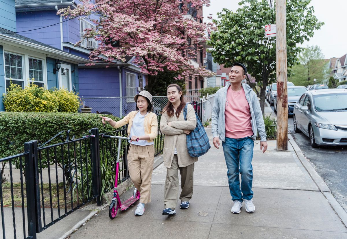 A family walking together along a residential pavement.