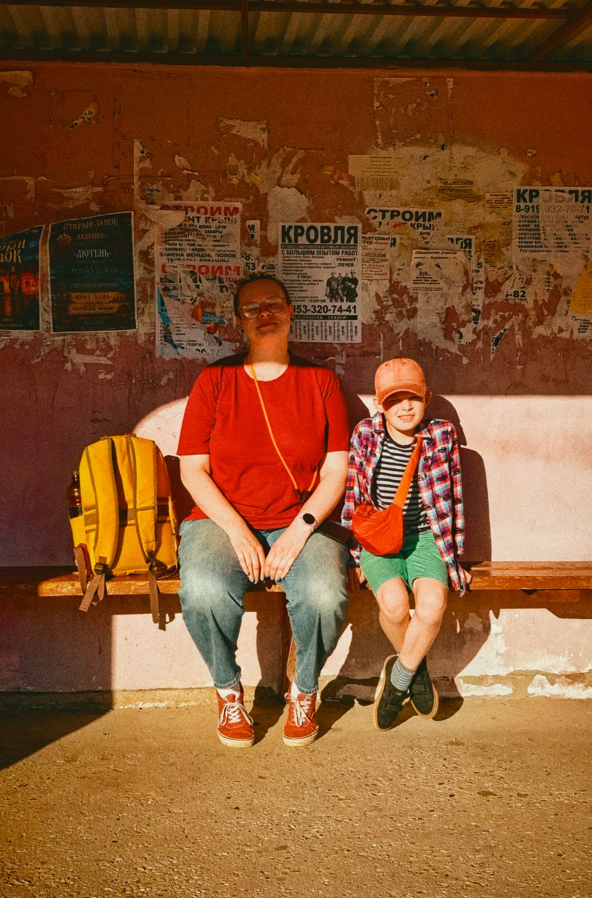 A woman and child sitting together at a bus stop.