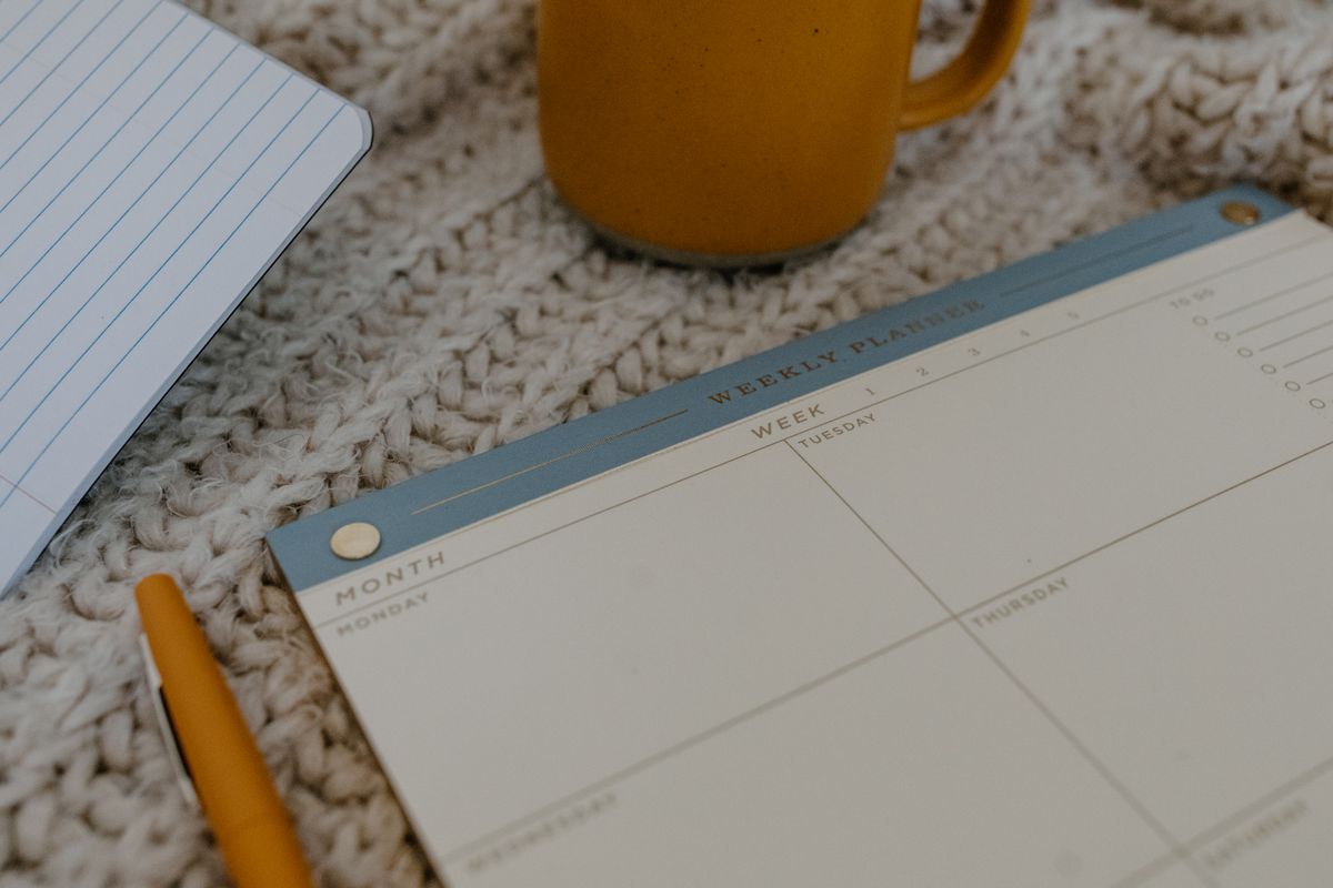 An open weekly planner resting on knitted fabric.