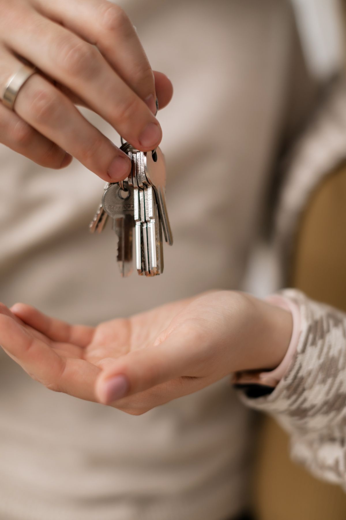 A hand passing house keys to another person.