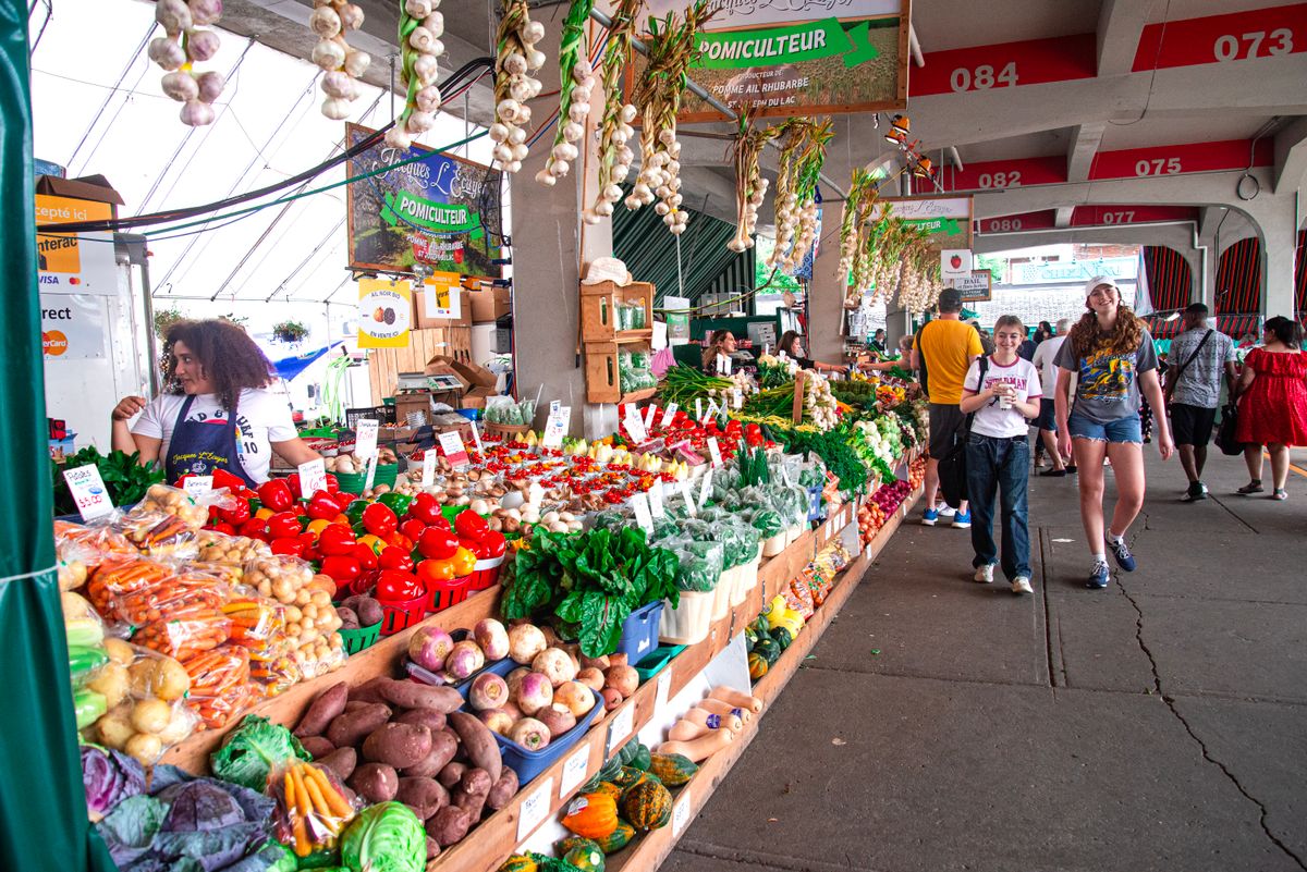 Produce stalls and shoppers at an outdoor market.