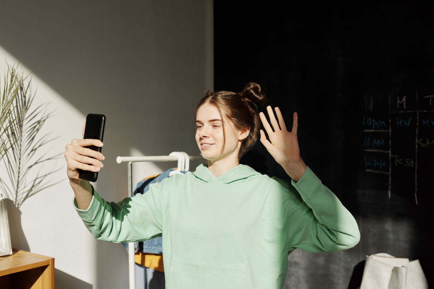 A teenager waving during a video call