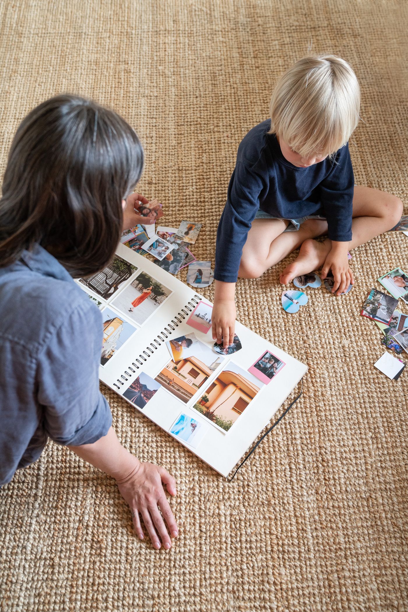 A parent and child assembling a scrapbook on the floor
