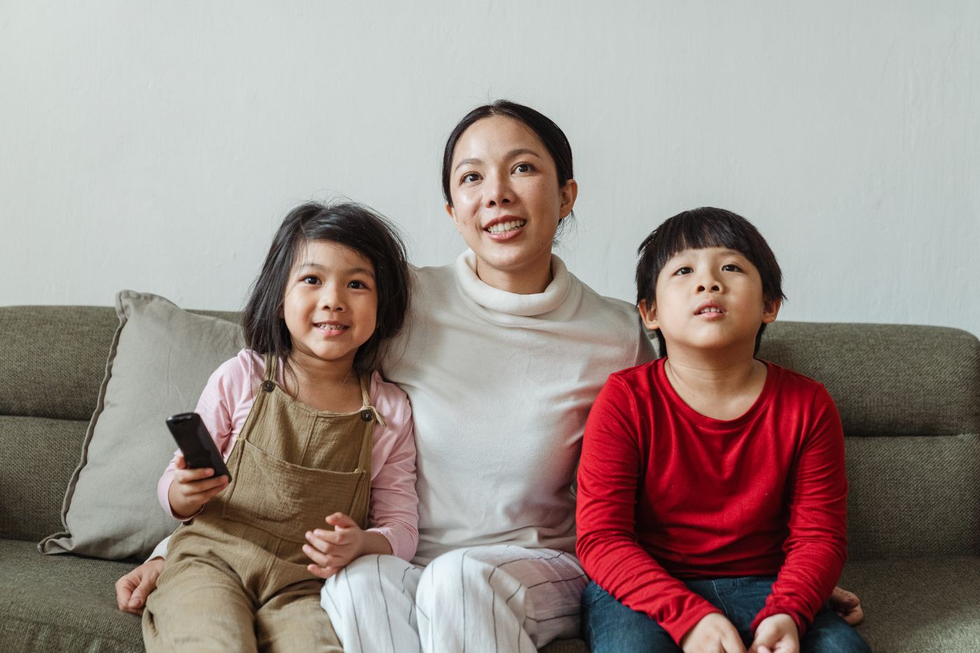 A mother and two children watching television together