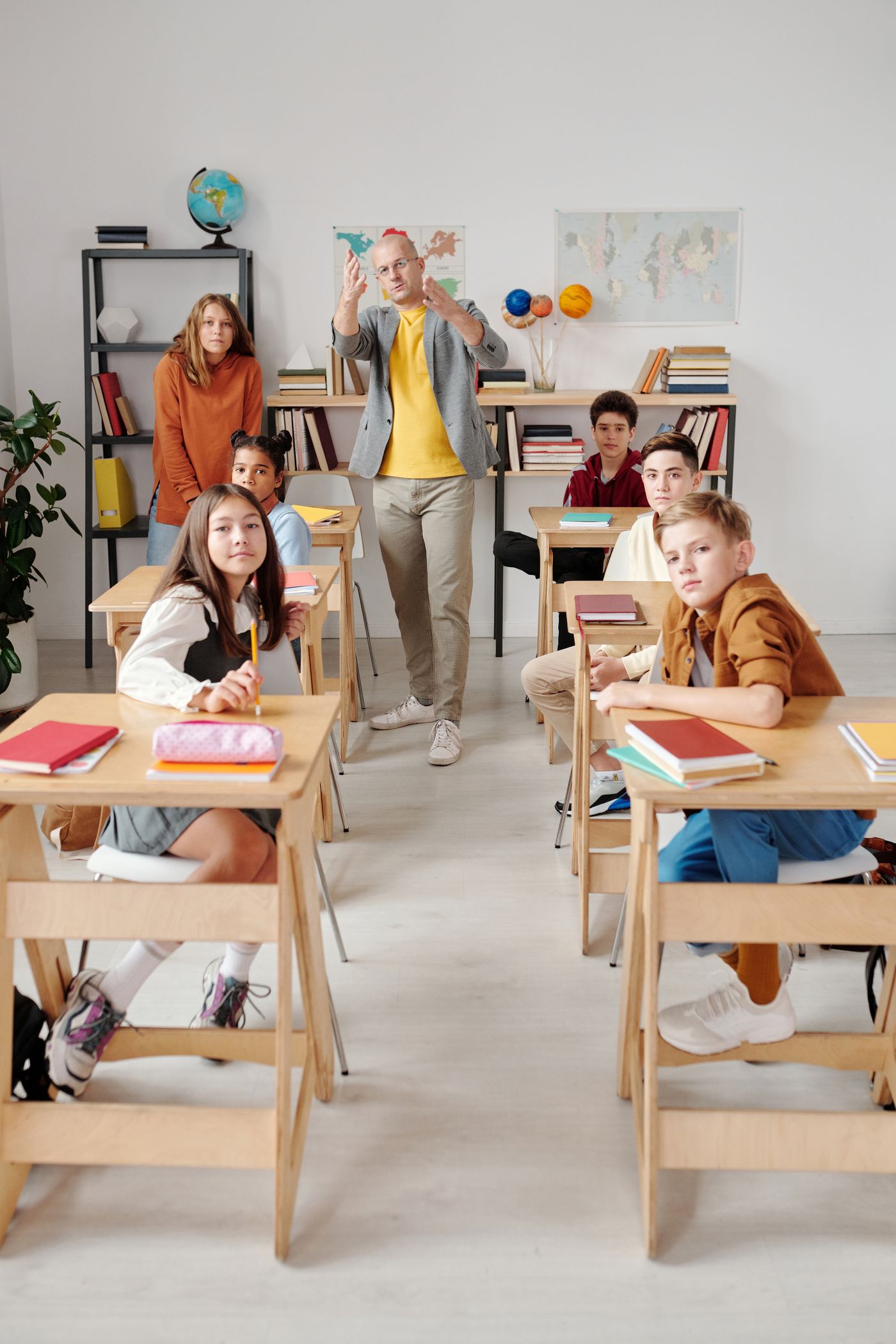 Teacher talking with students at their classroom desks