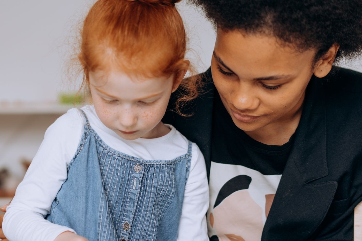 An adult and a child looking at work together at a table