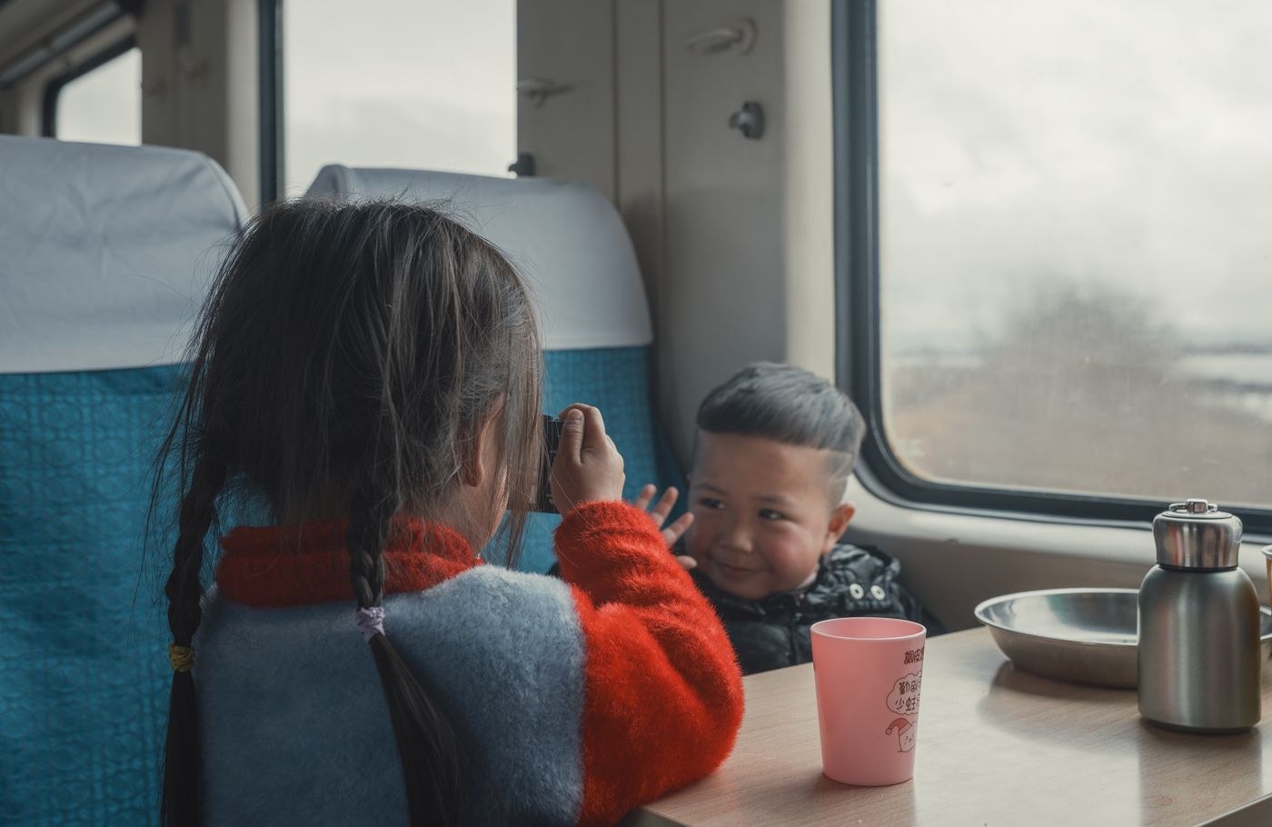 Two children sitting at a table inside a train carriage