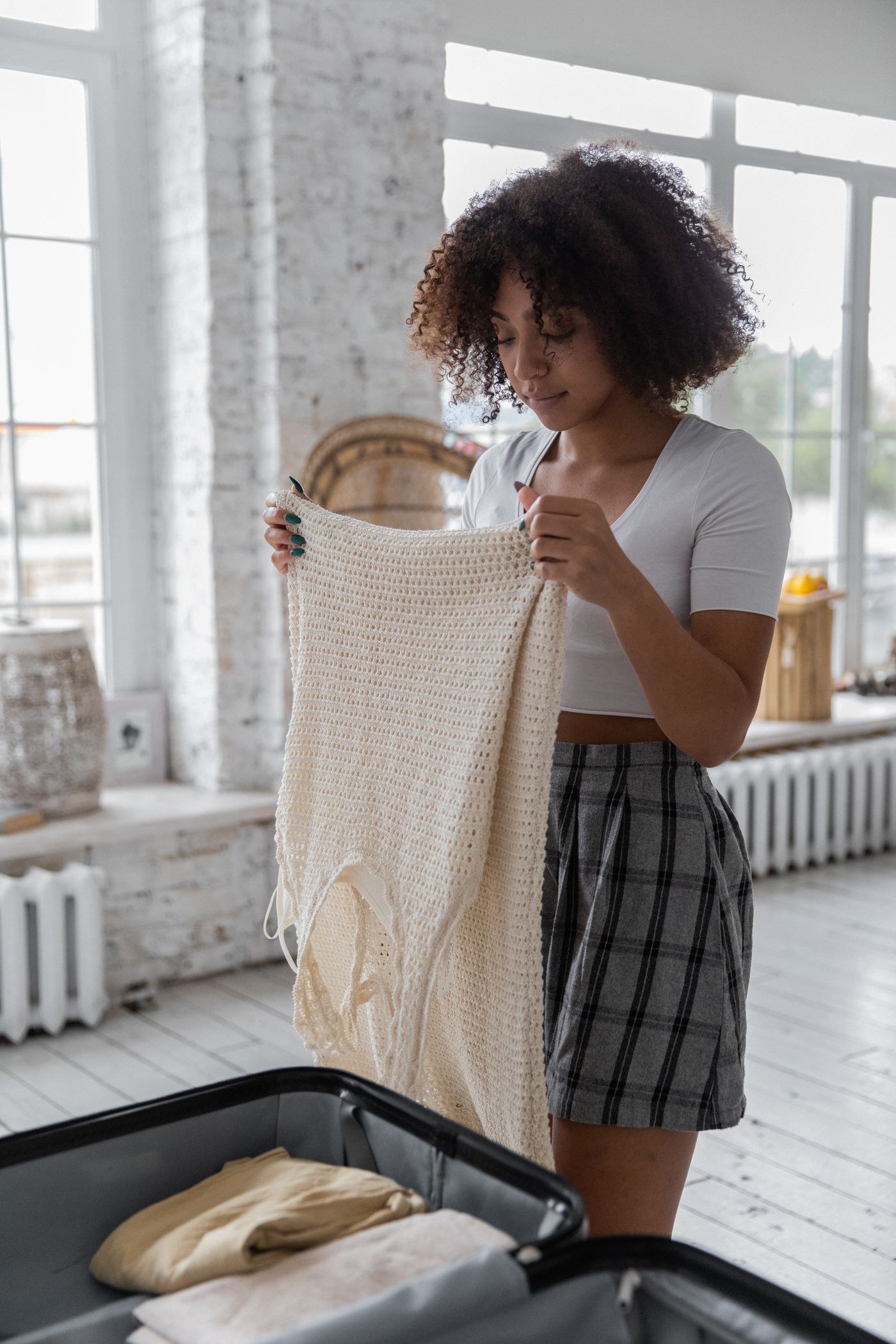 A woman holding clothing above an open suitcase